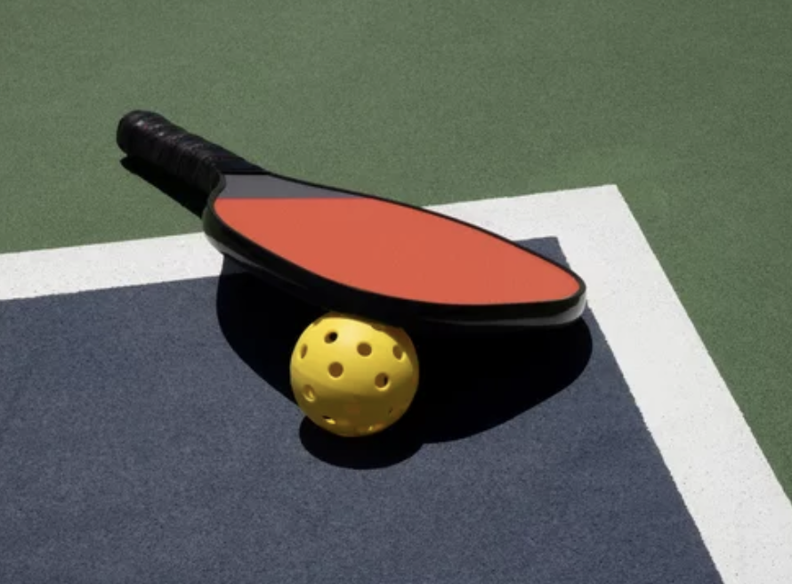 pickleball paddle and ball laying on pickeball court