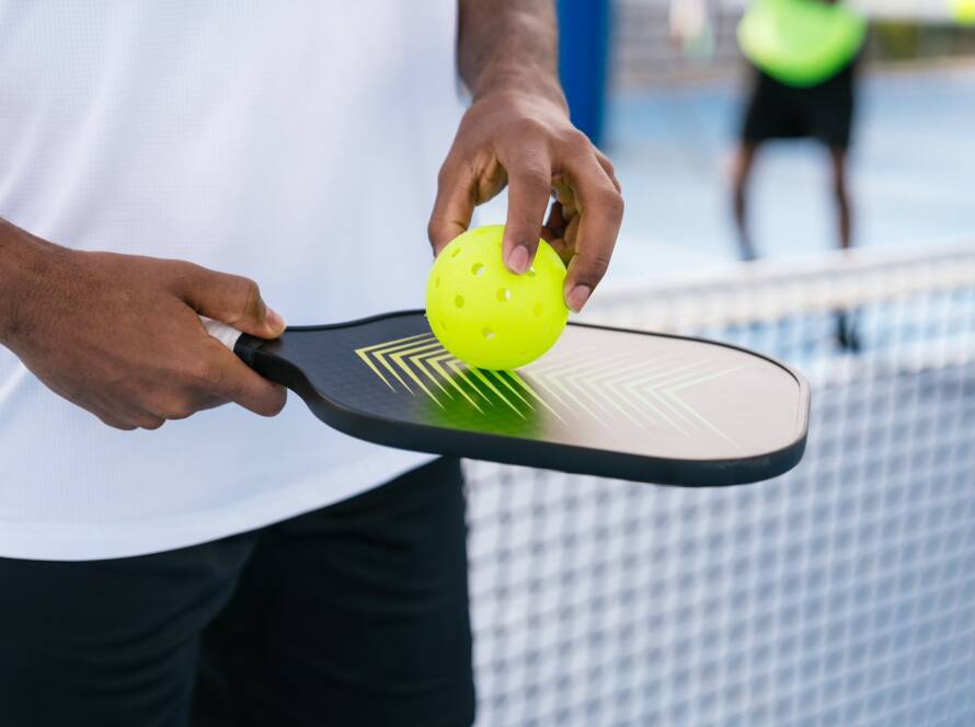 player holding pickleball paddle and ball close up