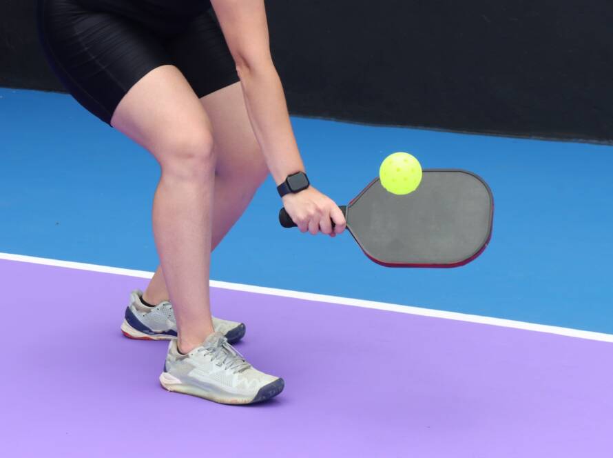 female pickleball player holding paddle hitting ball