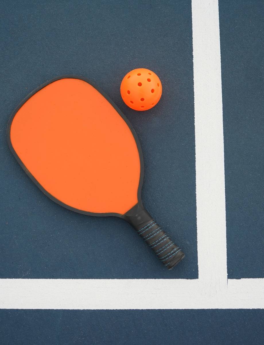 Pickleball paddle with pickleball on pickleball court.